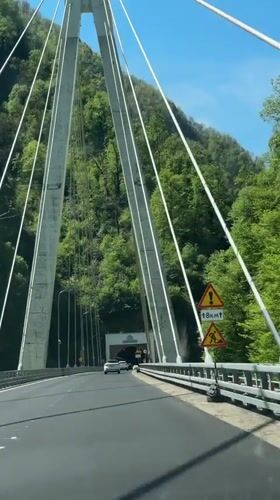 White car crosses suspension bridge toward tunnel in Kepsha