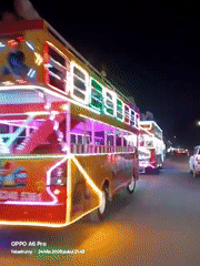 Nighttime festivities observed in urban park with illuminated buses, rides