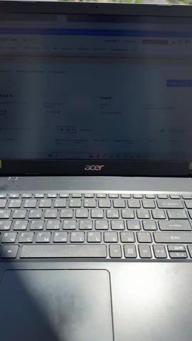 The video shows an Acer laptop sitting on a balcony. The screen displays a website with Russian text. A metal railing is visible behind the laptop, leading to a view of buildings, greenery, and the ocean in the distance. The laptop keyboard is visible in detail. The video shifts its focus, gradually revealing the surrounding view from the balcony.