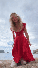 Woman in red dress performs playful stunts at Budva waterfront