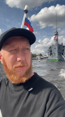 Small boat alongside a grey warship on the Saint Petersburg waterfront