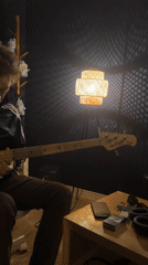 Musician plays bass guitar in dimly lit Paris room