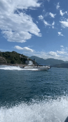 Crowded motorboat cruises Nha Trang waters near forested hills