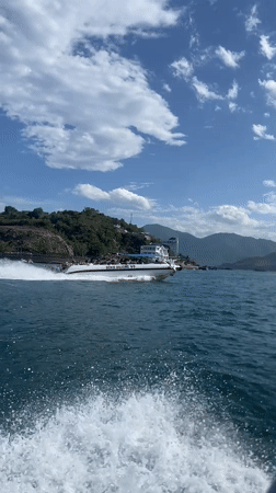 Crowded motorboat cruises Nha Trang waters near forested hills