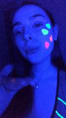 Woman displays neon makeup art under UV lighting in Russia