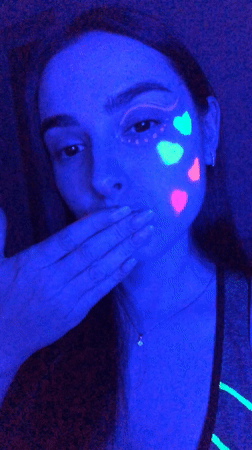 Woman displays neon makeup art under UV lighting in Russia