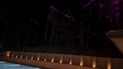 Evening backyard gathering features dining, fire pit, illuminated pool