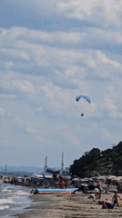 Tandem paraglider cruises over beach and forest near Burgas