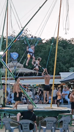 Kids bouncing on a bungee trampoline at a beachside attraction