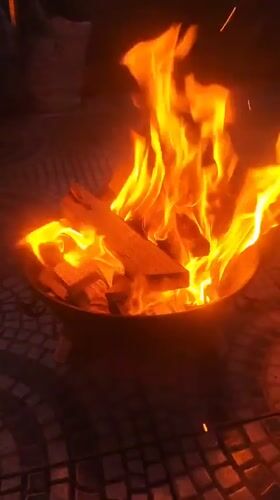 Fire burns in metallic pit on tiled surface in Ribeira Grande