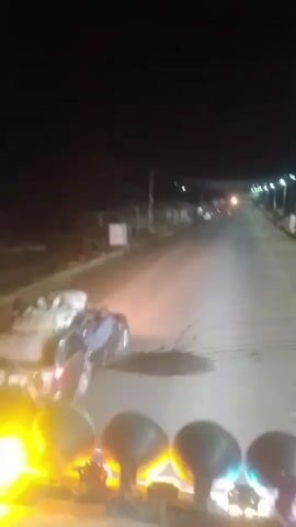 The video, taken at night, shows a car driving down a road with several bundles strapped to its roof. The recording seems to be taken from a vehicle following behind, focusing first on the car in front and then shifting inside the vehicle itself, revealing a cargo of what appears to be dead animals. The road is illuminated by streetlights, and the environment appears to be a sparsely populated or rural area.