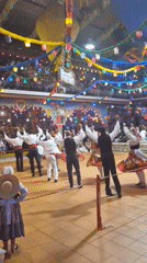 Traditional folk dancing fills a decorated hall in Darque