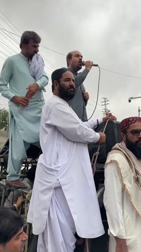 Street gathering with speakers and security presence in Quetta