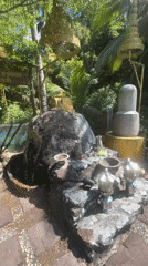 Person strikes gong at tropical shrine in Thailand