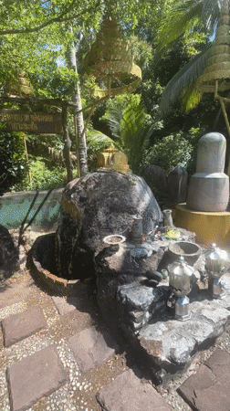 Person strikes gong at tropical shrine in Thailand
