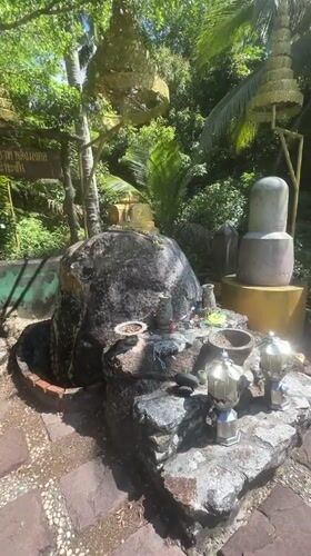 Person strikes gong at tropical shrine in Thailand