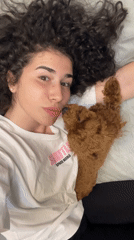 Woman and brown poodle share playful moments on bed