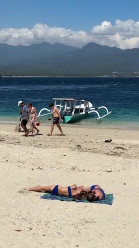 Sunny beach day with boats, clear water, and mountain views