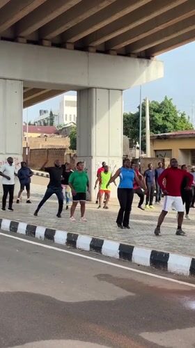 Outdoor group exercise class under a Jos overpass