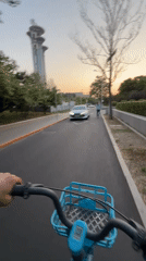 Cyclist rides blue bike past Beijing landmarks in Chaoyang District