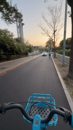 Cyclist rides blue bike past Beijing landmarks in Chaoyang District