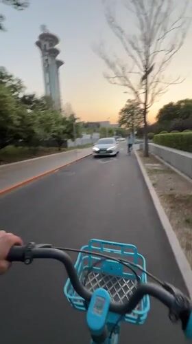 Cyclist rides blue bike past Beijing landmarks in Chaoyang District