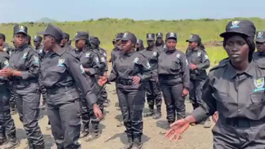 Here is a brief description of the video: 

The video shows a group of women wearing what appears to be a uniform of a dark color. They are standing in formation on what looks like a gravel road, with fields visible in the background. The women are engaging in coordinated dance movements.