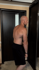 Man poses, flexes muscles in mirror at dawn