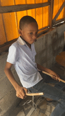 Boy plays drums as children gather in Iranla, Nigeria