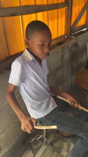 Boy plays drums as children gather in Iranla, Nigeria