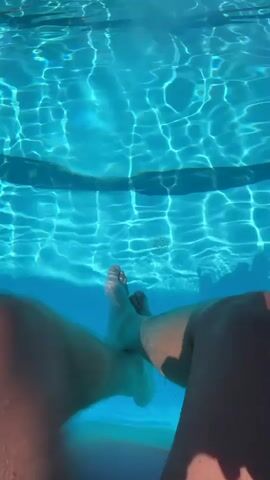 This media file provides a first-person perspective from within a swimming pool. The clear blue water is illuminated by sunlight, creating rippling patterns on the pool floor and steps. The camera is submerged, looking down into the water.

The primary subjects are the legs and feet of a person visible in the upper portion of the frame, submerged in the water. These appear to be bare feet with visible toes. The legs are also underwater.

The activity is swimming or relaxing in a pool. The camera appears to be moving slightly, perhaps as the person is kicking their legs or shifting position.

Notable details include the bright sunlight, suggesting it is daytime, likely a sunny day suitable for swimming. The water is a vibrant turquoise blue, indicating it is likely a clean and well-maintained swimming pool. The pool has visible steps, also submerged and illuminated by the sunlight, with darker lines demarcating the edges of the steps. In the upper part of the first frame, above the water's surface, a dark line or edge is visible, possibly the side of the pool or a pool float. The overall mood conveyed is one of relaxation and enjoyment of a sunny day at the pool.

While there is no visible text within the media file itself, the provided location context is Vicenza, Italy.