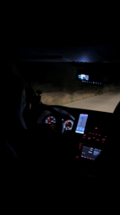 Woman drives at night with phones on dashboard