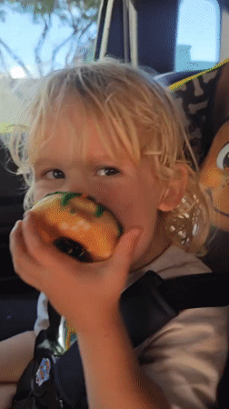 Child enjoys green-iced donut in car seat, Florida Keys