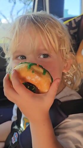 Child enjoys green-iced donut in car seat, Florida Keys