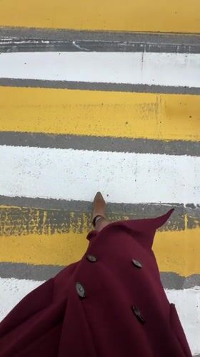 Pedestrian crosses street in burgundy coat in Ufa
