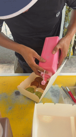 Person prepares miniature pancakes with colorful toppings in Kuala Lumpur