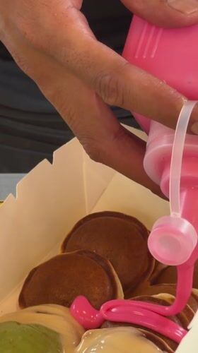 Person prepares miniature pancakes with colorful toppings in Kuala Lumpur