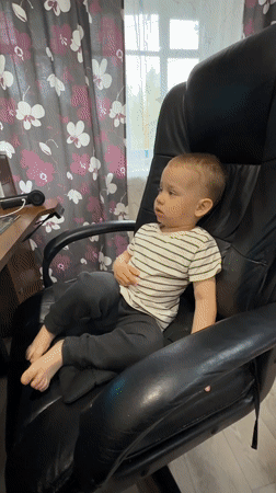 Toddler uses gaming computer at home desk in Russia