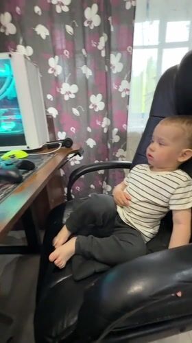 Toddler uses gaming computer at home desk in Russia