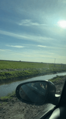 Vehicle travels muddy road near stream in Great Yarmouth