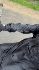 Motorcyclist rides through morning rain in Huế, Vietnam