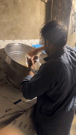 Man pours yellow liquid into steel container in Quetta