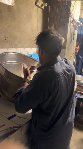 Man pours yellow liquid into steel container in Quetta