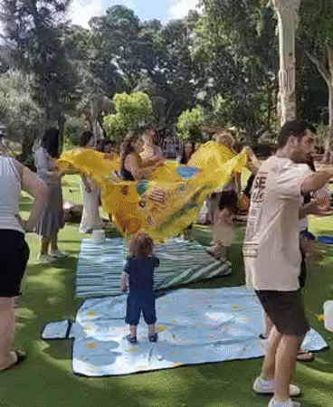 Outdoor group activity with large yellow object in Tel Aviv park