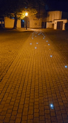 Blue lights illuminate brick pathway in Lutherstadt Eisleben at night