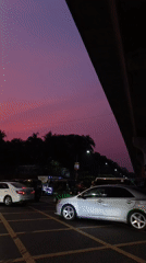 Evening traffic observed at urban intersection under colorful dusk sky