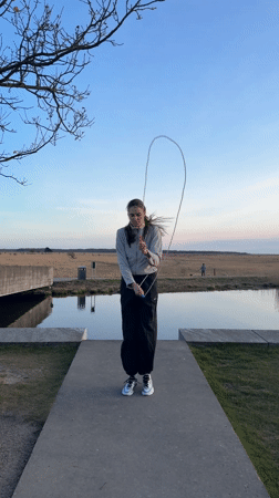 Woman jump ropes in Copenhagen park on sunny afternoon
