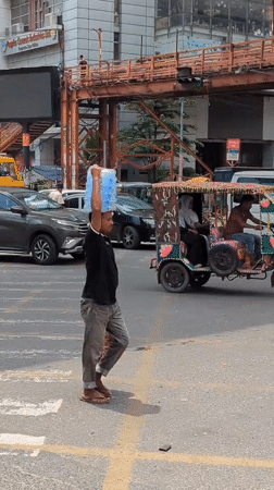 Street-level hustle on a Dhaka road: water, wheels, and fish