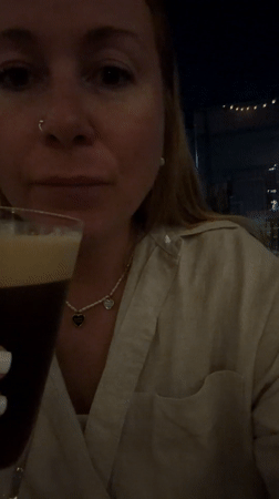 Woman enjoys dark beverage at Cape Town bar evening
