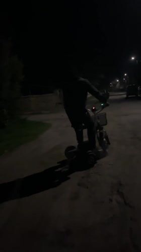Person rides, repairs electric scooter on dark Bulgarian road